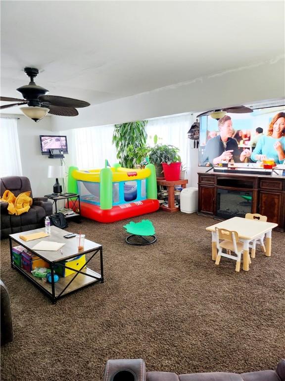 playroom with ceiling fan, carpet, and a fireplace