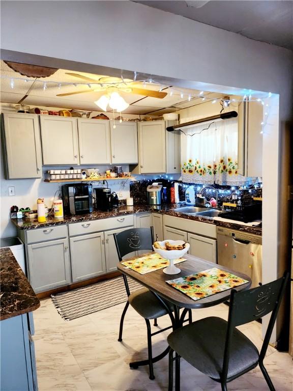 kitchen featuring dishwasher, a sink, and dark stone countertops