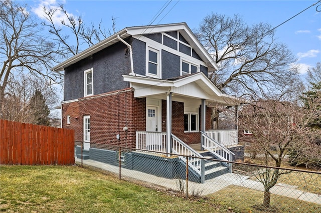 view of front of house featuring brick siding, fence, a front lawn, and stucco siding