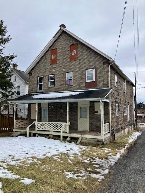 view of front of home with a porch and brick siding