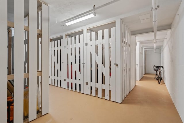 hall featuring concrete block wall and concrete flooring