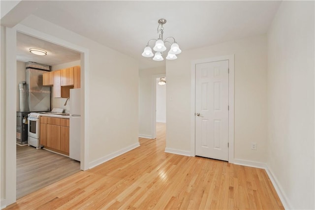 unfurnished dining area featuring light wood-style floors, baseboards, and a chandelier