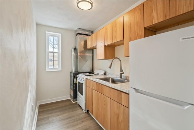 kitchen featuring white appliances, light wood-style flooring, baseboards, and a sink