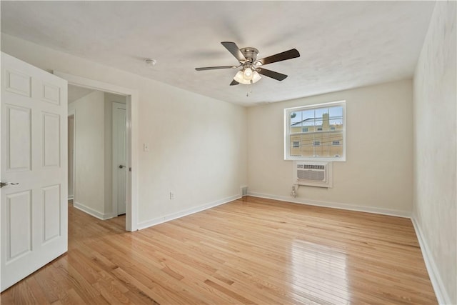 spare room featuring ceiling fan, light wood finished floors, a wall unit AC, and baseboards