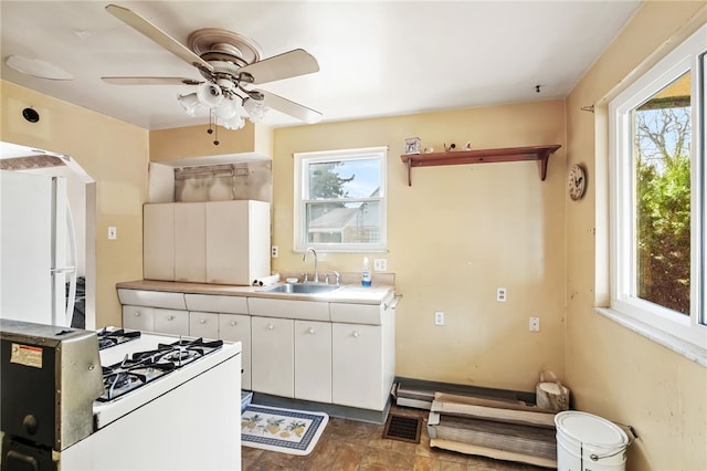 kitchen featuring white appliances, visible vents, light countertops, white cabinetry, and a sink