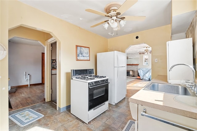 kitchen featuring arched walkways, ceiling fan, white appliances, a sink, and light countertops