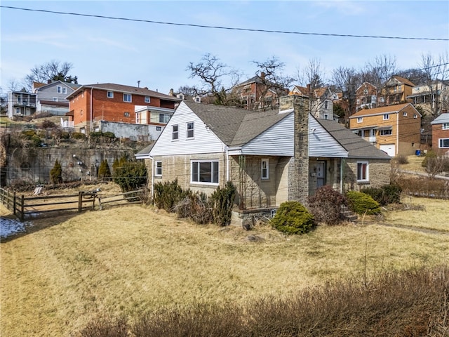 back of house with a chimney, a residential view, fence, and a lawn