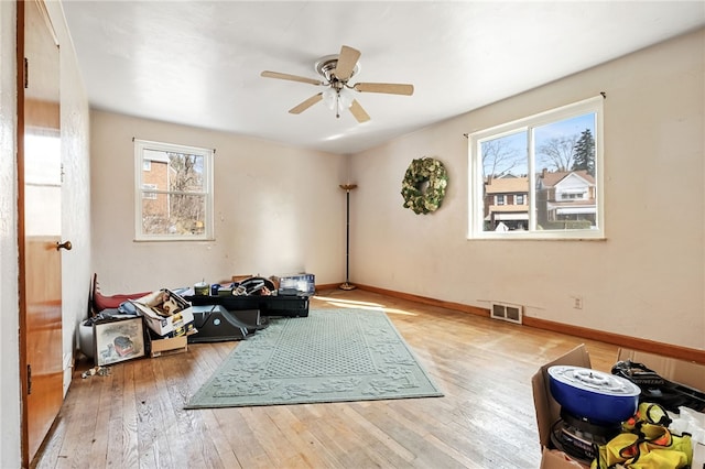 living area with light wood-type flooring, baseboards, visible vents, and ceiling fan