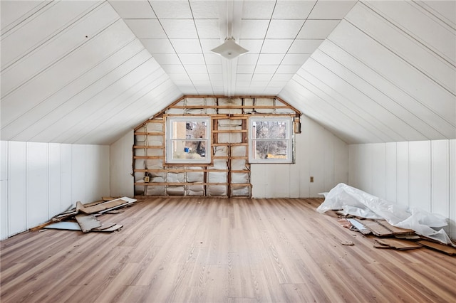 additional living space with light wood-style floors and vaulted ceiling