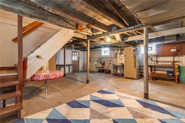 basement featuring stairway, a sink, and heating unit