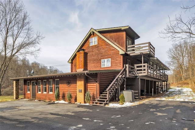 view of front facade with central AC, stairway, and a wooden deck