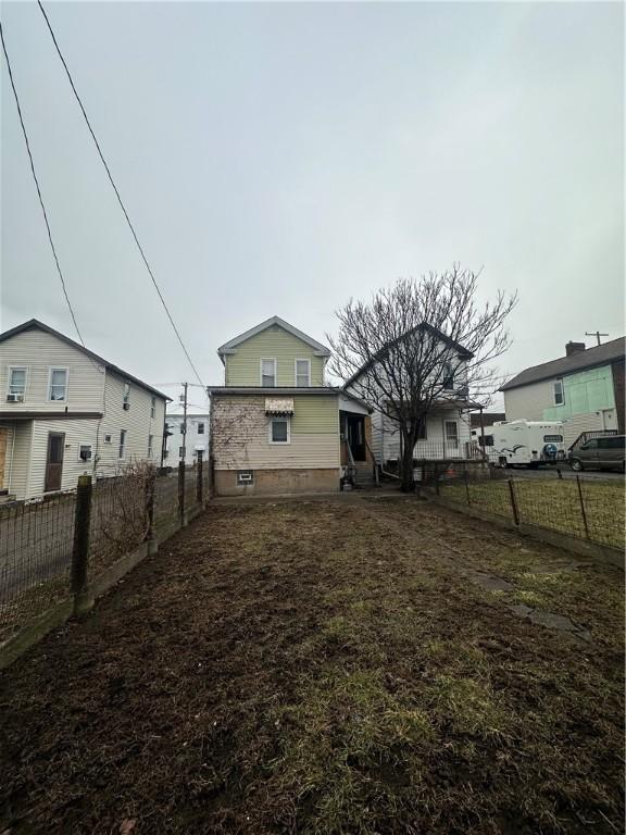 rear view of house featuring a fenced backyard