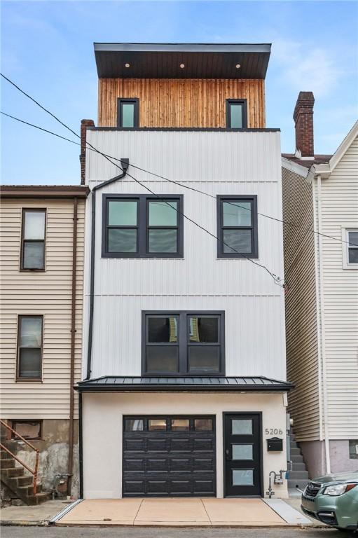 contemporary house featuring metal roof, stairway, a standing seam roof, and an attached garage