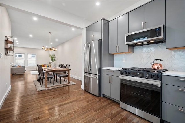 kitchen featuring dark wood-type flooring, light countertops, appliances with stainless steel finishes, gray cabinets, and backsplash