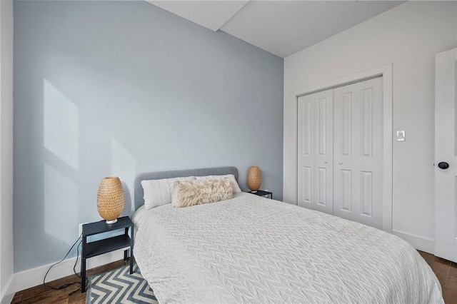 bedroom featuring dark wood-style floors, baseboards, and a closet