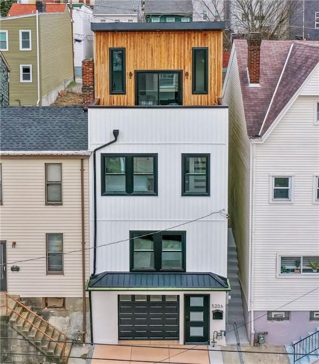 view of front of home with a garage, a standing seam roof, driveway, and metal roof