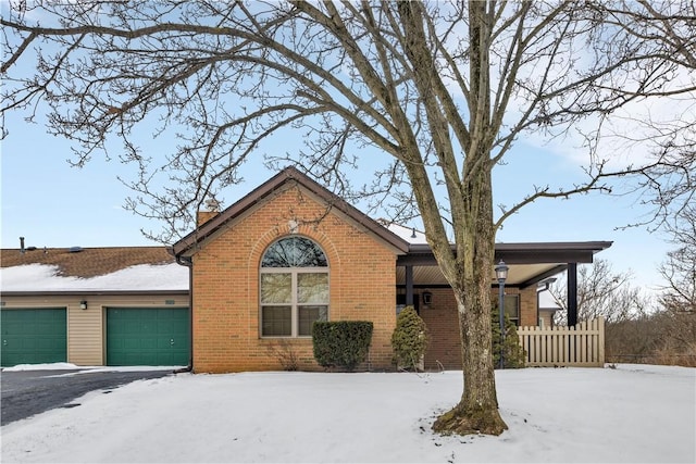 view of front facade featuring brick siding, fence, a chimney, and an attached garage