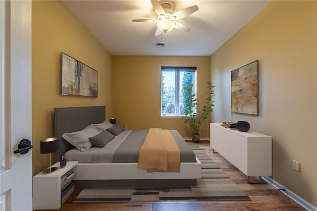 bedroom featuring baseboards, visible vents, ceiling fan, and wood finished floors