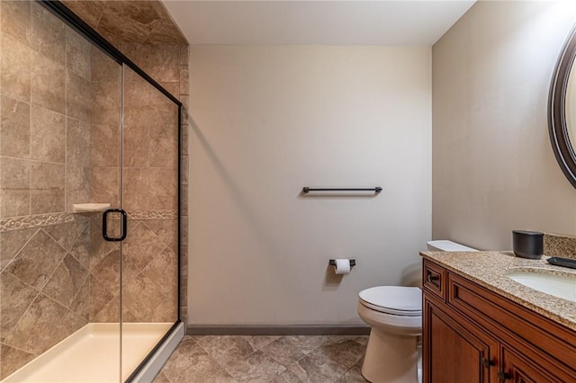 bathroom with a stall shower, baseboards, vanity, and toilet