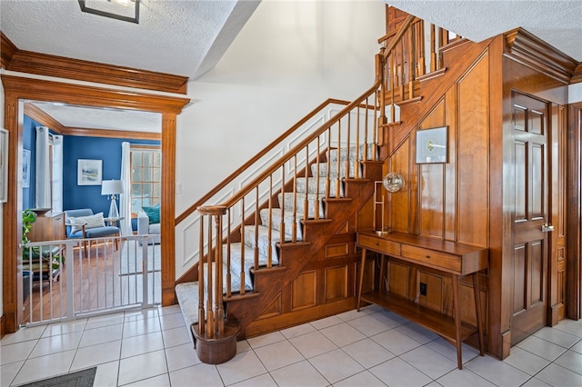 stairs with a textured ceiling, tile patterned flooring, and crown molding