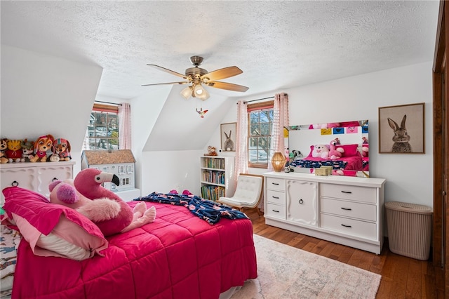 bedroom with a textured ceiling, a ceiling fan, vaulted ceiling, and wood finished floors