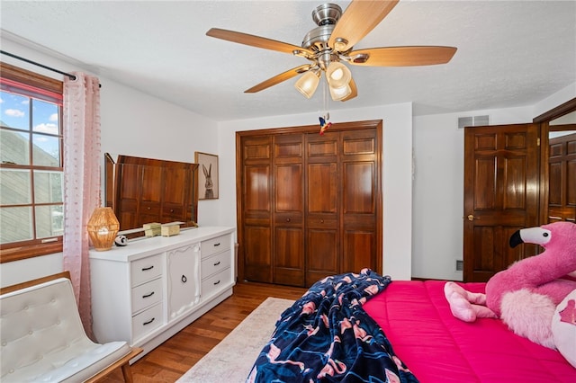 bedroom with a textured ceiling, ceiling fan, visible vents, a closet, and light wood finished floors