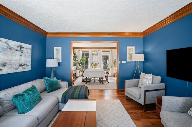 living area with ornamental molding, a textured ceiling, and wood finished floors