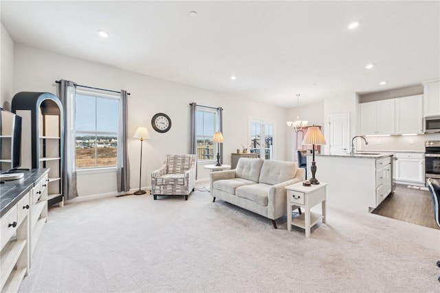 living room with light carpet, recessed lighting, baseboards, and an inviting chandelier