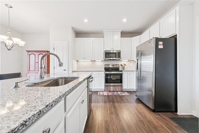 kitchen with dark wood finished floors, hanging light fixtures, appliances with stainless steel finishes, white cabinetry, and a sink