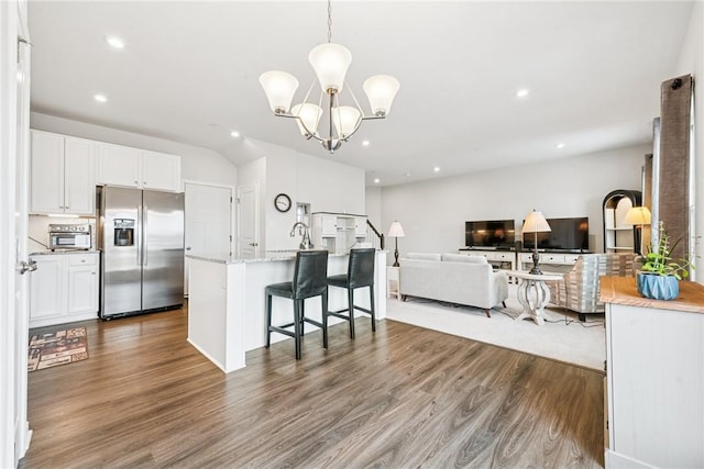 kitchen with white cabinetry, stainless steel refrigerator with ice dispenser, wood finished floors, and open floor plan