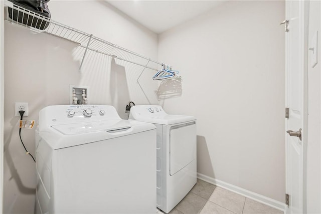 washroom featuring laundry area, baseboards, washing machine and clothes dryer, and light tile patterned flooring