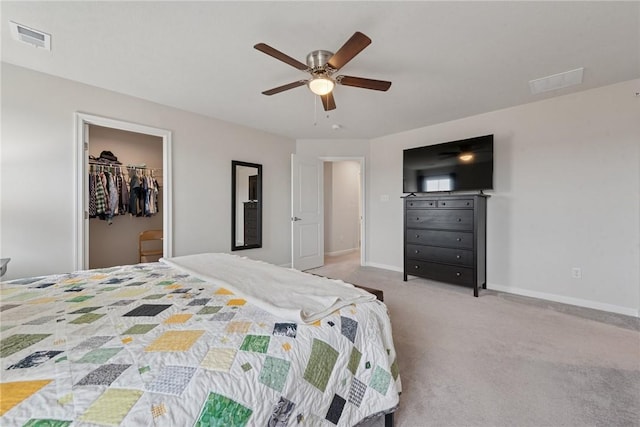 bedroom featuring light colored carpet, a walk in closet, visible vents, and baseboards