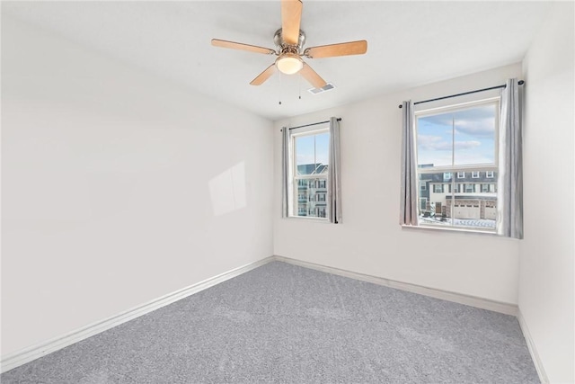 carpeted spare room featuring visible vents, plenty of natural light, and baseboards