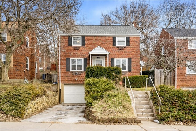 view of front of house with a garage, a chimney, concrete driveway, and brick siding