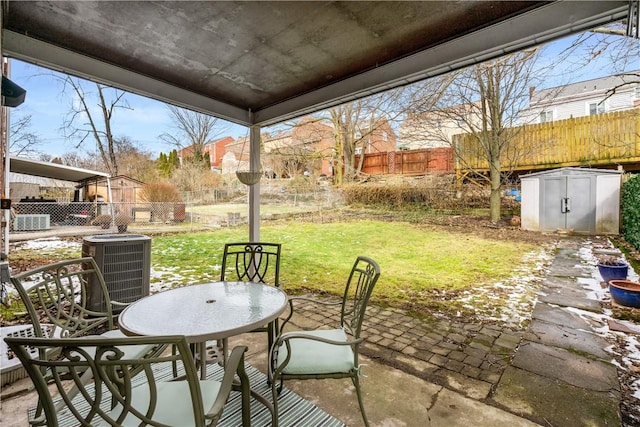 view of patio with outdoor dining area, a fenced backyard, an outdoor structure, and a storage shed