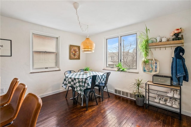 dining space featuring dark wood-style flooring, visible vents, and baseboards