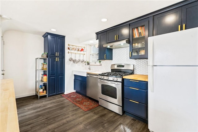 kitchen featuring stainless steel appliances, decorative backsplash, glass insert cabinets, a sink, and under cabinet range hood