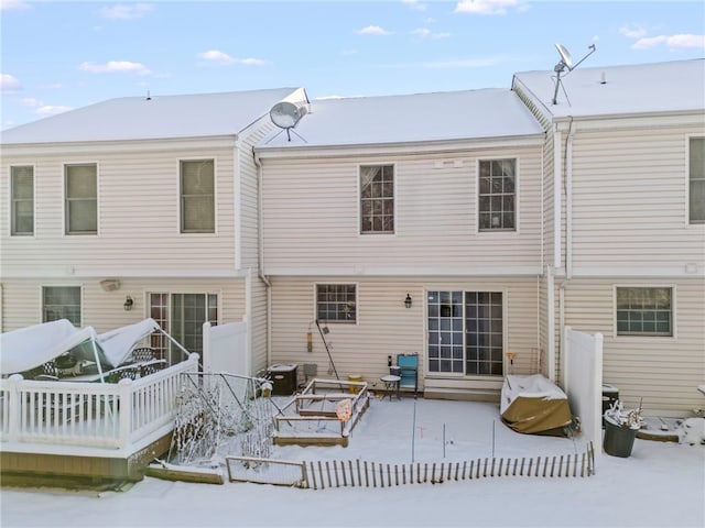 snow covered back of property featuring a deck