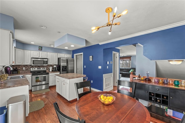 kitchen with appliances with stainless steel finishes, dark countertops, a sink, and white cabinetry