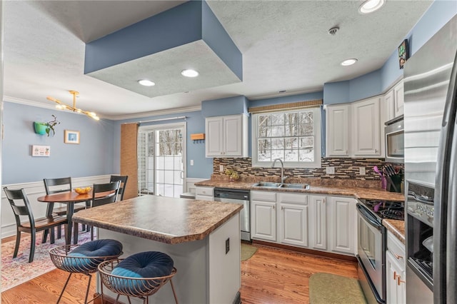 kitchen featuring a kitchen island, appliances with stainless steel finishes, white cabinets, and a sink