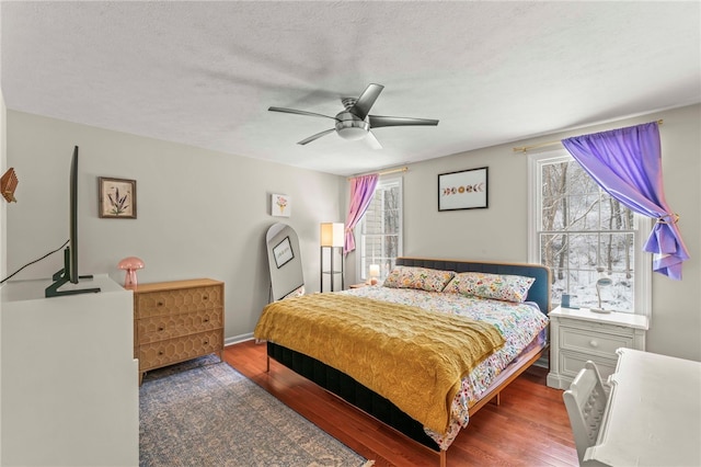 bedroom featuring dark wood-style floors, ceiling fan, and a textured ceiling