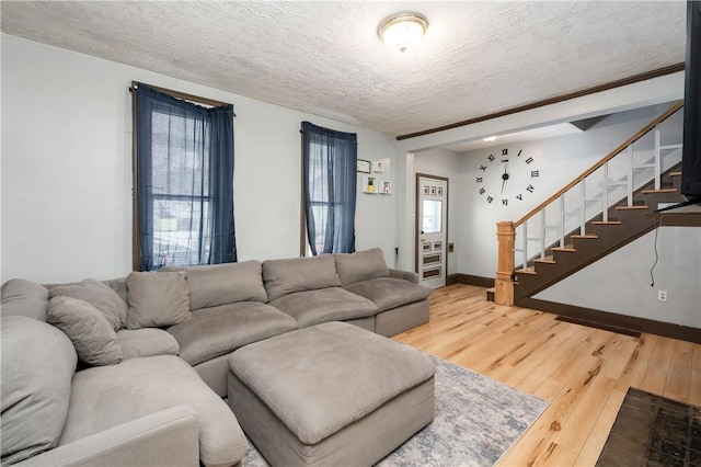 living area featuring a textured ceiling, stairway, wood finished floors, and baseboards