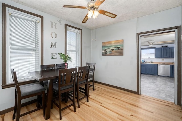 dining room with a ceiling fan, light wood-type flooring, a textured ceiling, and baseboards