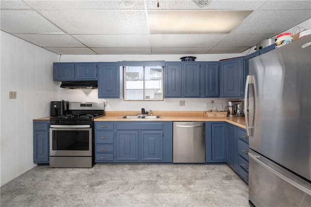 kitchen featuring blue cabinetry, stainless steel appliances, light countertops, a sink, and under cabinet range hood