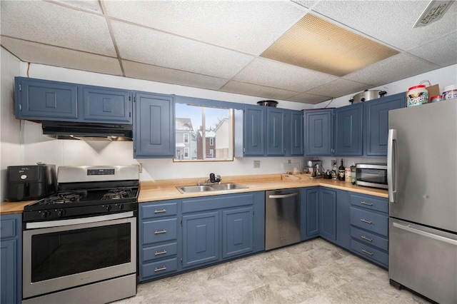 kitchen featuring under cabinet range hood, appliances with stainless steel finishes, light countertops, and a sink