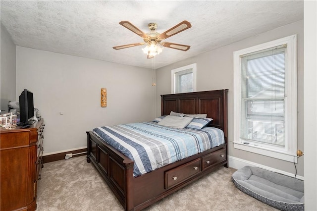 bedroom with a ceiling fan, light carpet, a textured ceiling, and baseboards