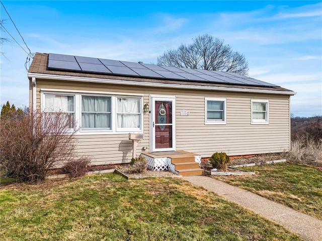 bungalow-style home with a front lawn and solar panels