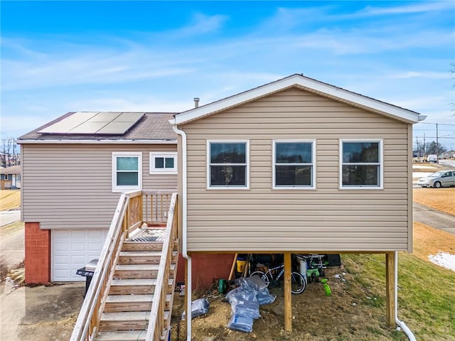 rear view of property featuring solar panels and an attached garage