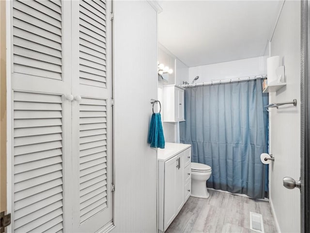 bathroom featuring toilet, wood finished floors, vanity, a closet, and shower / bath combination with curtain