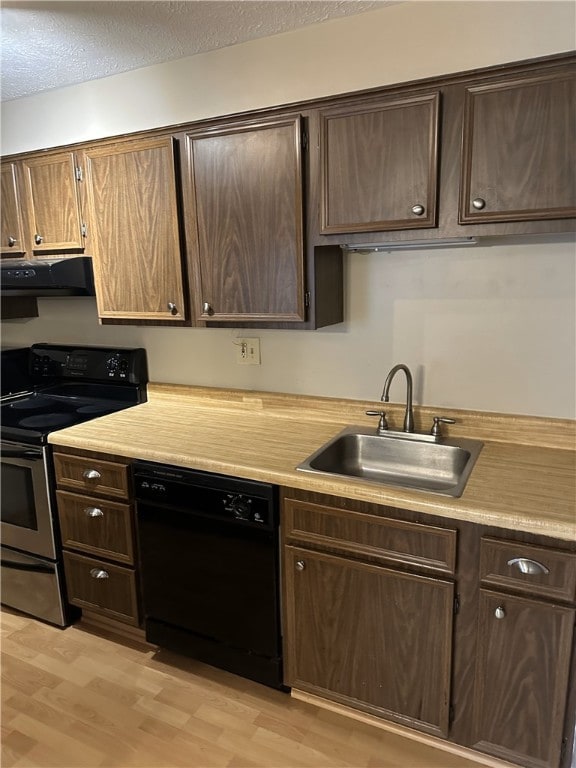 kitchen with black dishwasher, light countertops, a sink, and stainless steel range with electric cooktop